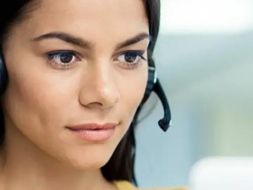 Крупним планом жінка в гарнітурі, яка дивиться прямо в камеру з професійним виразом обличчя.