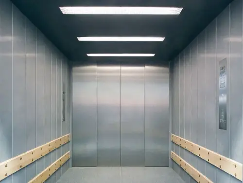 Просторий сучасний вантажний ліфт з інтер'єром з нержавіючої сталі та дерев'яними перилами